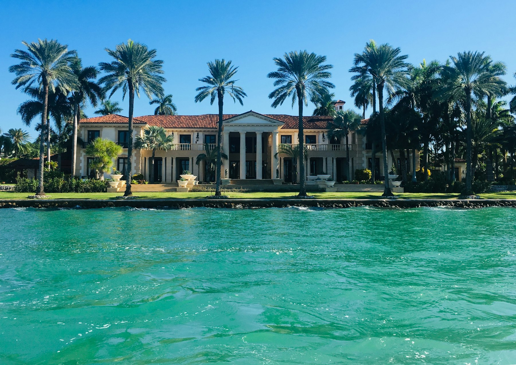 Waterfront estate with palm trees on aqua water